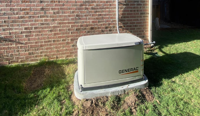 A Generac generator installed next to a brick wall.